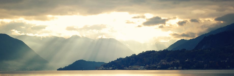 image of sun rays bursting through clouds over a lake